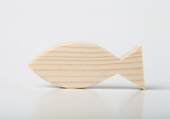 A figurine of a fish or horse mackerel, carved from solid pine with a hand jigsaw. On a white background