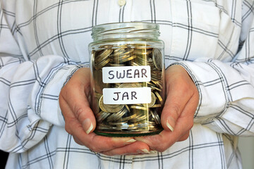A Glass Jar Labelled Swear Jar Full Of Cash