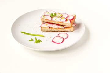 Toasted toast with fresh chopped radishes and green herbs on the white plate. Healthy breakfast. Sandwich with vegetable.