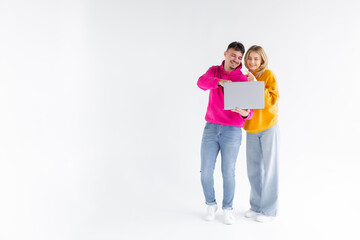 Full length image of excited couple man and woman rejoicing while holding laptop together isolated over white background