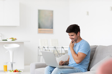 Young man with laptop in his living room, freelancer