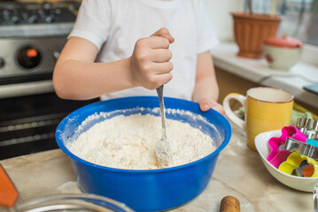 The hands of a child who mixes the dough. Cooking at home