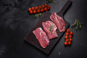 Raw duck breast with herbs and spices on a dark concrete background
