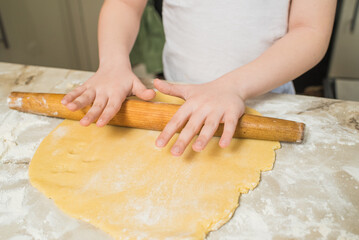 Child hands of a chef who rolls the dough at home in the kitchen. Cooking at home