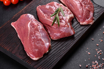 Raw duck breast with herbs and spices on a dark concrete background