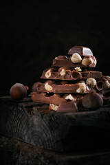 Pile of hazelnut milk chocolate and nuts on dark background