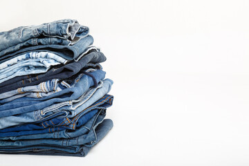 Stack of old blue jeans, cut pieces ready for recycling and scissors on white background. Circular...