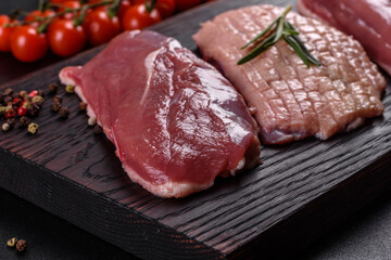 Raw duck breast with herbs and spices on a dark concrete background