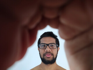 Obraz premium View of asian young man through hand with wearing specs - stock photo