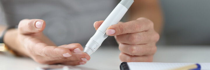 Woman holding lancet near her finger to measure blood glucose closeup - obrazy, fototapety, plakaty