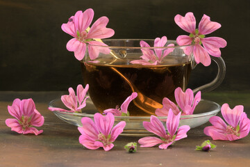 Hibiscus tea and hibiscus flowers in a glass cup on a wooden table. Vitamin tea for colds and flu.