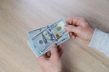old male hands hold paper dollars banknotes in his hands, counting a bundle of money, concept of cash, payments, savings