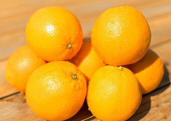 Oranges à presser humides exposées au soleil sur une table en bois