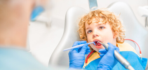 Pretty little boy in dental office, having his teeth checked by female dentist .