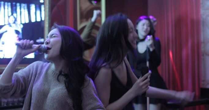 Happy young friends singing karaoke in nightclub,4K