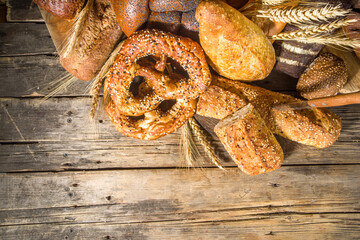 Assortment of various delicious freshly baked bread, on wooden rustic background copy space