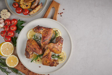 Roasted chicken wings in barbecue sauce and mixed vegetable salad with pepper seeds rosemary, salt in white plate on light color stone table. top view with copy space. tasty snack. Flat lay.