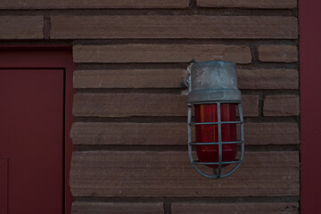 Old style vintage red light alert light on front of fire department station brick building zillah...