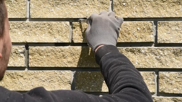 Builder completes the work on the wall cladding. The process of stitching. Construction works.