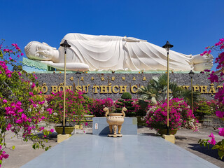 Lying Buddha statue with flowers in the Vinh Trang Temple in Mytho City. Mekong Delta, Vietnam.
