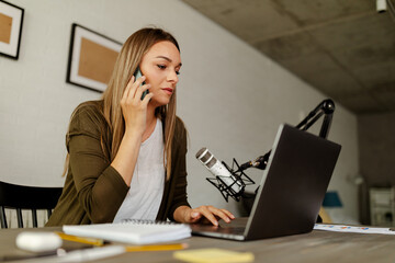 Young Caucasian woman talking on phone at her desk in an office.