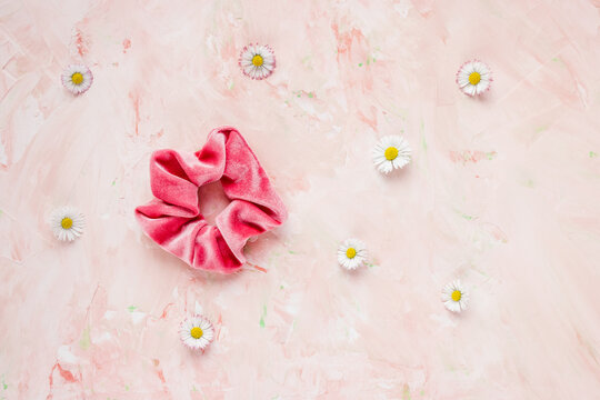 One trendy velvet scrunchie and fresh spring flowers on pastel backround. Flat lay, top view. Diy accessories, hairstyle, lifestyle, spring and summer outfit ideas concept, copy space