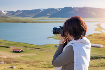 Woman photographer shooting photos with her professional camera of a majestc coastal scenery at sunset