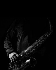 fotografía de stock de un saxofonista con abrigo negro posando con su saxofón para portada