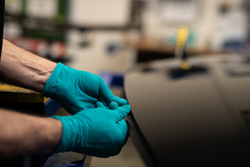 worker with gloves assembling rubber in canopy car glass in automotive plant