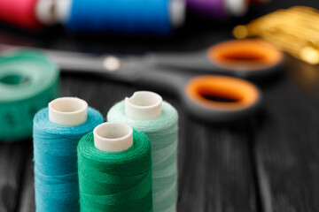 Colorful sewing utensils on black wooden surface