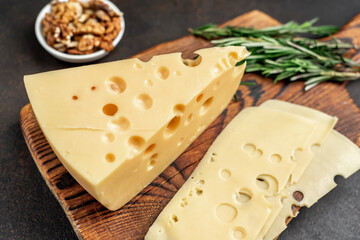 Maasdam cheese with walnut and rosemary on stone background