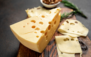 Maasdam cheese with walnut and rosemary on stone background