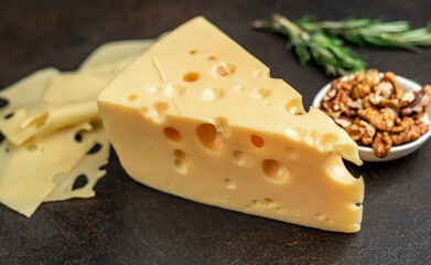 Maasdam cheese with walnut and rosemary on stone background