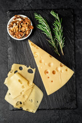 Maasdam cheese with walnut and rosemary on stone background