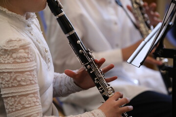 Schoolgirl in a white sweater at a music lesson in a school orchestra playing a musical instrument...