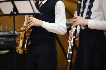 A duet of young musicians, a boy with a saxophone and a girl with a clarinet play at a music lesson...