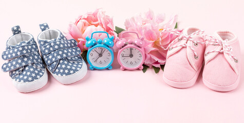 Girl and boy shoes with pink and blue watches on pink background. Baby birthday, invitation or greeting card mockup. Banner. Copy space.