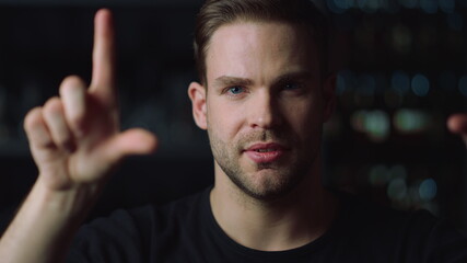 Portrait of handsome young man swiping on invisible multi touch screen in office