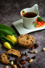 one white cup of tea and yellow and red tulips