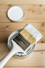 Top view on white paint brush on the opened can on the wooden table or floor painting and...
