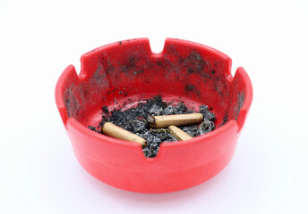 Top angle, zoom in view of cigarettes in a red ashtray.