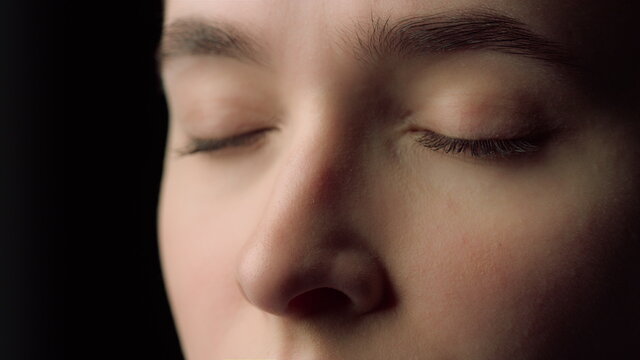 Macro of female face beauty resting with closed eyes in black studio.Tired woman
