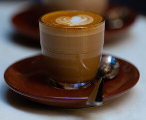 decorated glass of Coffee Piccolo Latte on a white table in a Sydney Cafe NSW Australia
