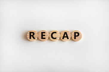 Recap symbol. The word 'recap' on wooden circles on beautiful white table. Beautiful white...