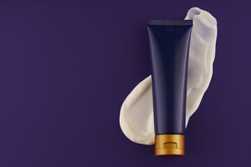 Cosmetic night cream tube with white smear swatch. Premium ads. Night cream in a blue bottle on a purple background, top view.