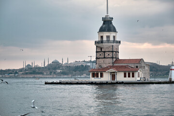 Fototapeta na wymiar 04.03.2021 istanbul Turkey. maiden tower during sunset and many seagulls flying in front of the tower with magnificent nature of turquoise water