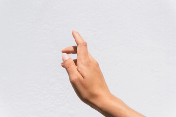 Closeup of reaching out hand sign against a white wall background