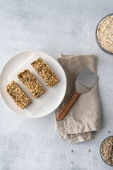Overhead view of home made gluten free granola bars on a plate  next to a serving spatula and linen napkin.