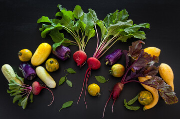 Assorted colorful garden vegetables on a black background.