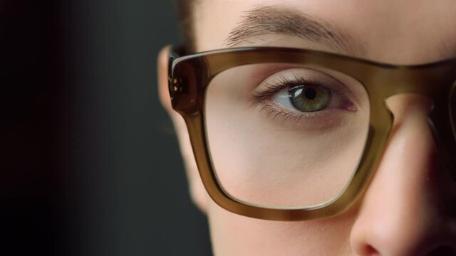 Macro of focused businesswoman eye looking straight at camera in office. 
